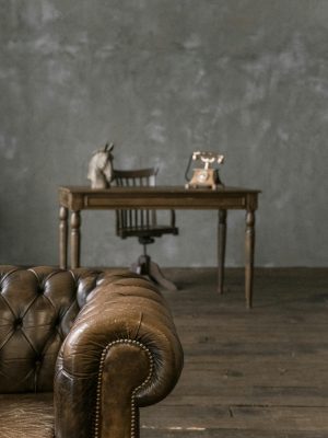 A classic styled room featuring a vintage leather sofa and a wooden desk with retro decor, exuding a timeless charm.