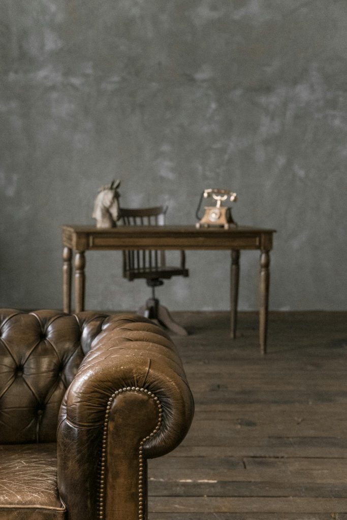 A classic styled room featuring a vintage leather sofa and a wooden desk with retro decor, exuding a timeless charm.