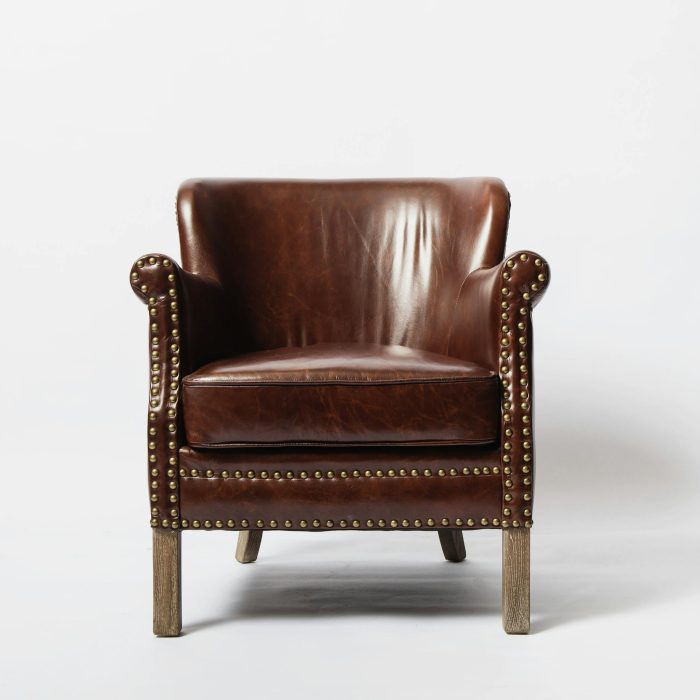 Classic brown leather armchair with wooden legs and studded details, perfect for cozy interiors.