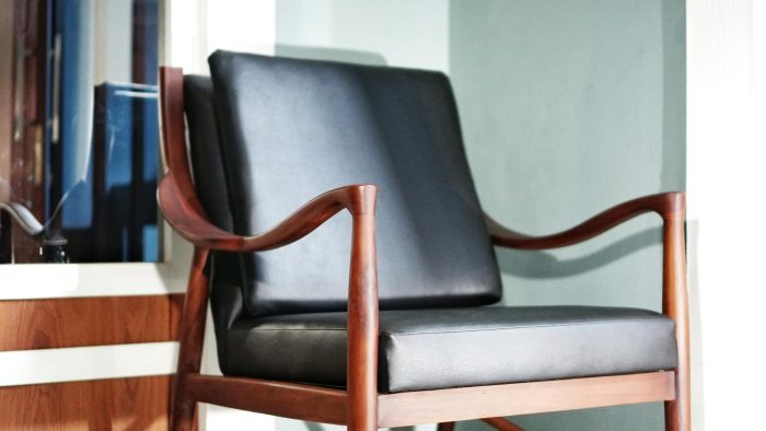 Close-up of a wooden chair with leather cushions in a modern interior setting.