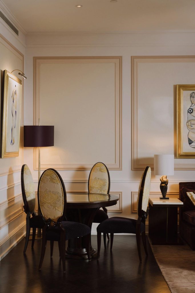 Elegant hotel room featuring luxurious chairs and a round table, highlighted by sophisticated interior design.