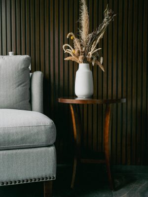 Stylish living room with grey sofa and vase on wooden table.