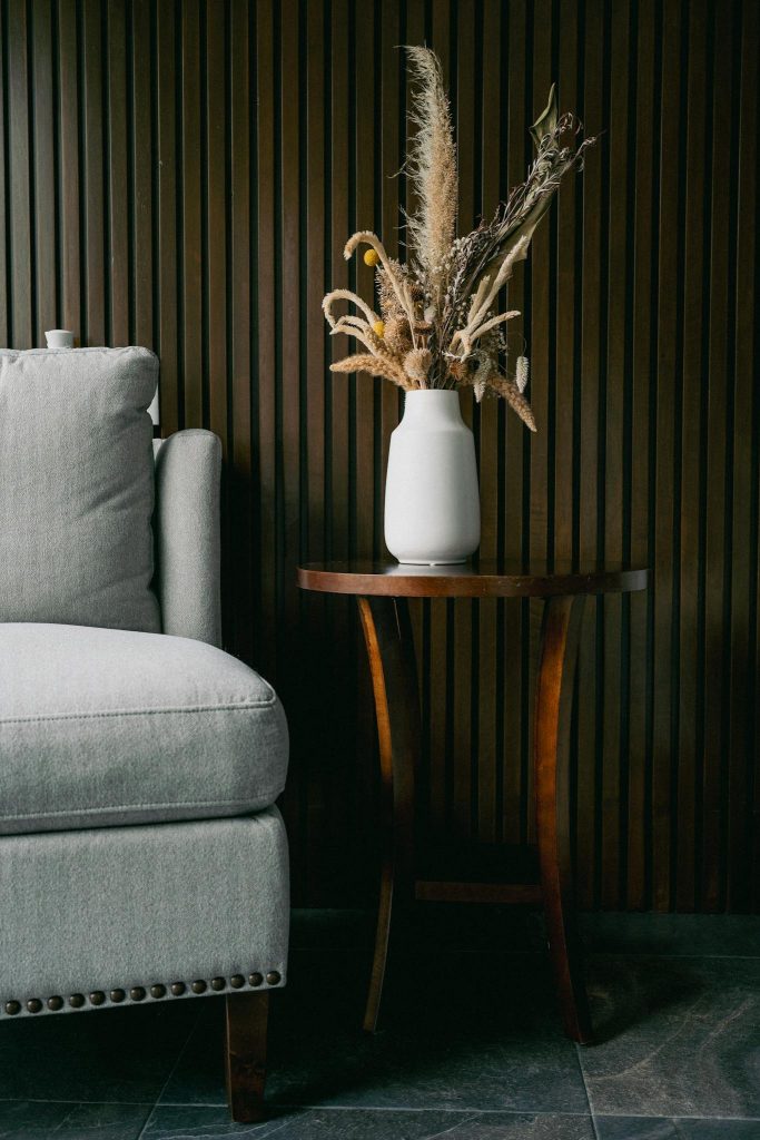 Stylish living room with grey sofa and vase on wooden table.